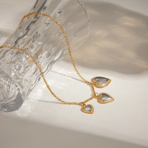 Detailed view of two-tone gold and silver heart pendants on a textured chain