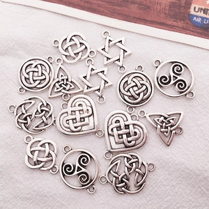 Detailed macro view of vintage silver Celtic knot and triskelion charms on white fabric