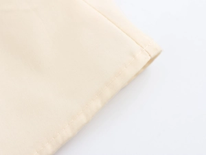 Makroaufnahme der feinen Nähte und der cremefarbenen Baumwollstruktur am Kleid