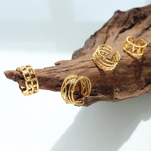 Set de cuatro anillos ajustables de acero de titanio chapados en oro sobre madera con fondo blanco