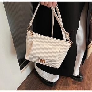 Gros plan sur la texture velours côtelé blanc et le fermoir doré rotatif du sac à main