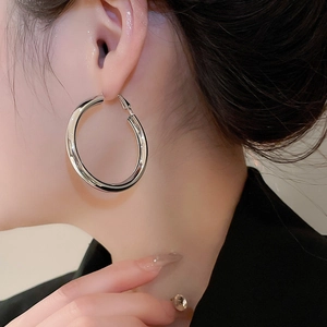 Close-up of model wearing polished silver hoop earrings with high-shine mirror finish