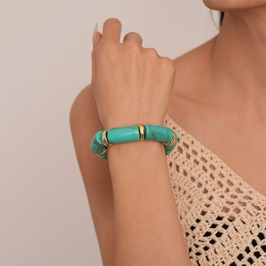 Detail of green acrylic bamboo beads and gold metal rings on a woman wrist