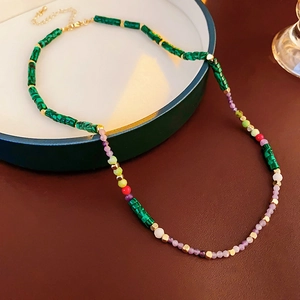 Detailed view of handmade beaded necklace with green tubes and golden spacers on leather