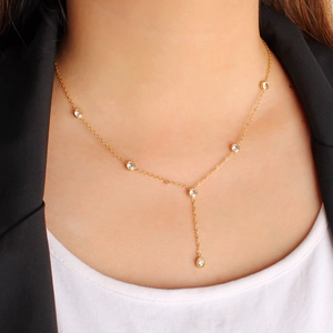 Close-up of elegant gold-tone Y-shaped necklace with round sparkling zircons on model