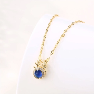 Golden reindeer necklace with blue gemstone and cubic zirconia on elegant white background