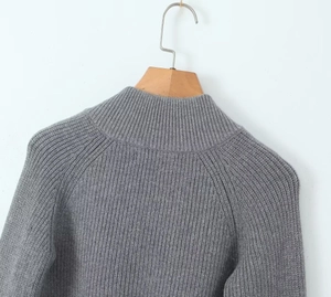 Close-up of the fine knit texture and raglan shoulder seam of a grey knitted cardigan