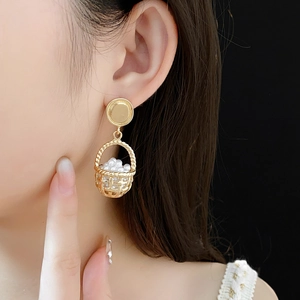 Close-up of vintage golden hollow basket earrings with white pearls on a model