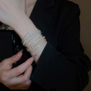 Detail of layered bracelet with sparkling rhinestones and white pearls on woman's wrist