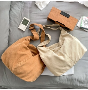 Detail view of brown and beige corduroy crossbody bags with adjustable straps on bed