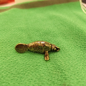 Antique brass sea lion miniature figurine with detailed texture on green background
