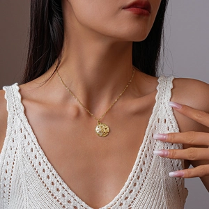 Elegante goldene Halskette mit einem hohlen runden Blumenanhänger an einem Model