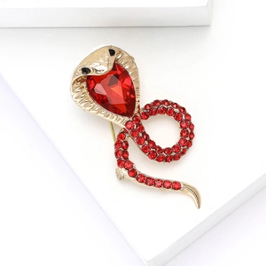 Detail of gold cobra brooch featuring large red center stone and ruby-colored rhinestones