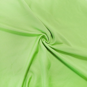 Detail of bright green knit fabric texture showing twisted draping and fine fiber structure