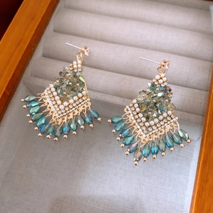 Detail of fan-shaped peacock blue crystal drop earrings with pearls on velvet display