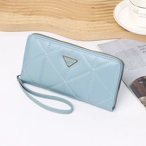 Detail view of light blue quilted long wallet with wristlet on a stylish lifestyle desk set