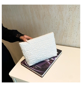 Close-up of white bubble textured fabric on a minimalist ruched clutch makeup bag