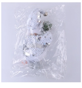 Close-up of Santa gnome doll with silver sequins and pine needle in plastic bag