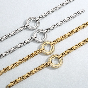Detail of gold and silver chunky chain bracelets with crystal pavé hollow heart charms