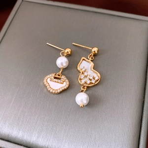Detailed macro view of asymmetric gold plated earrings with pearl and zircon inlay