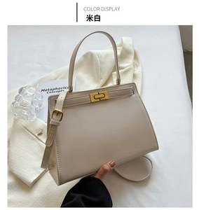 Detailed view of a cream white leather crossbody bag featuring gold hardware and rotating lock
