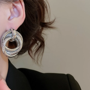 Detail of silver layered hoop earrings on a model wearing a black blazer