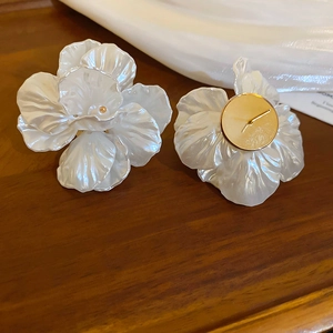Detail of white 3D acrylic flower earrings with golden bases and pearl finish