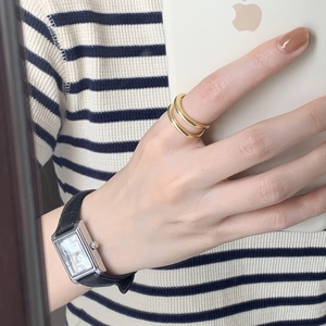Minimalist double-layered gold ring paired with classic black leather strap watch