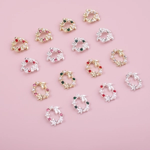 Détail de charmes à ongles couronne de Noël avec perles blanches et strass colorés