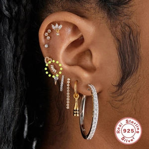 Macro shot of S925 sterling silver ear studs set with zircon stones on female ear cartilage