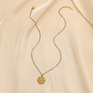 Detail view of a vintage gold coin zodiac pendant on soft beige silk background