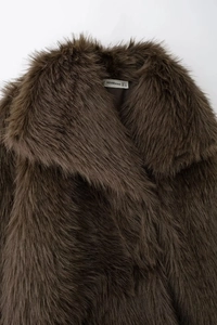 Gros plan sur une veste en fausse fourrure marron foncé avec col large et étiquette interne