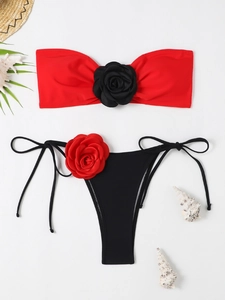 Flat lay of a two-piece bikini with 3D floral accents and beach-themed props