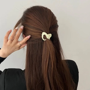 Close-up of a cream-colored acrylic hair claw clip securing a ponytail on a model