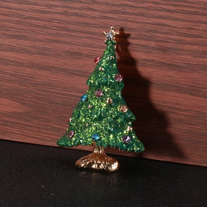 Detailed view of enamel Christmas tree brooch with green glitter and colorful rhinestones