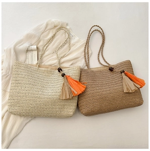 Detail of straw woven tote bags with colorful tassels and wooden beads on white fabric