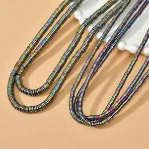 Detailed view of rainbow metallic hematite disc beads arranged on a ceramic tray