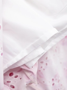 Vue macro détaillée de broderie ajourée blanche et rose avec des coutures précises