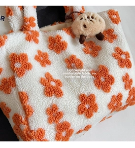 Nahaufnahme der weißen Plüschtasche mit orangen Blumen und weichem Tieranhänger