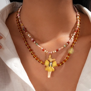 Detail of bohemian layered necklace with amber beads and yellow fairy pendant on a model