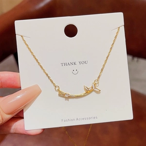 Elegant gold fishtail pendant necklace with cubic zirconia inlay on display card