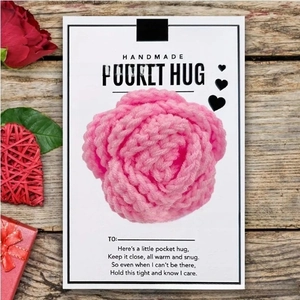 Pink crocheted heart on Pocket Hug card placed on a rustic wood background
