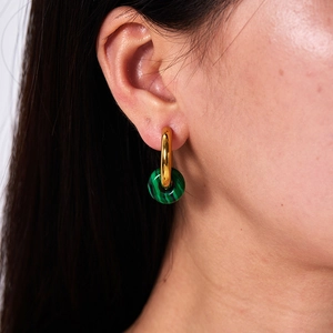 Close-up of gold stainless steel hoop earrings with green malachite stone pendant on model