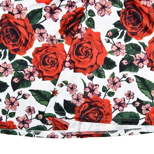 Macro detail of white floral fabric featuring red rose prints and high-quality hem stitching