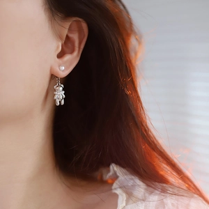Detailed view of silver bear pearl earrings with a two-way wear style on human ear