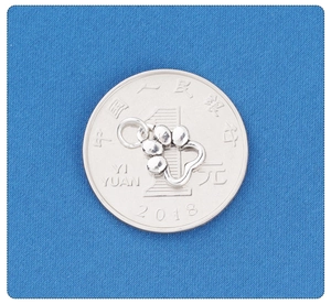 Detail shot of a small silver cat paw pendant showing size comparison on a one yuan coin