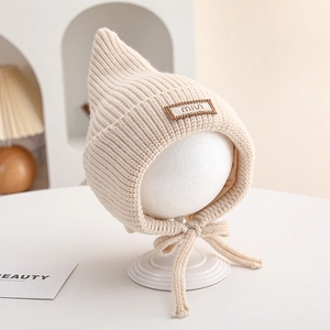 Close-up of beige knit baby pointed hat with soft ribbed texture and chin straps