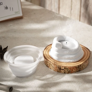 Detailed view of white snake-shaped candle on wooden stand with frosted glass holder