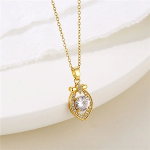 Macro detail of gold bow necklace with heart pendant and sparkling zircon inlay