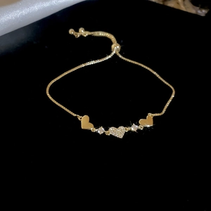 Detail of gold box chain bracelet featuring a zircon pavé heart and polished side charms